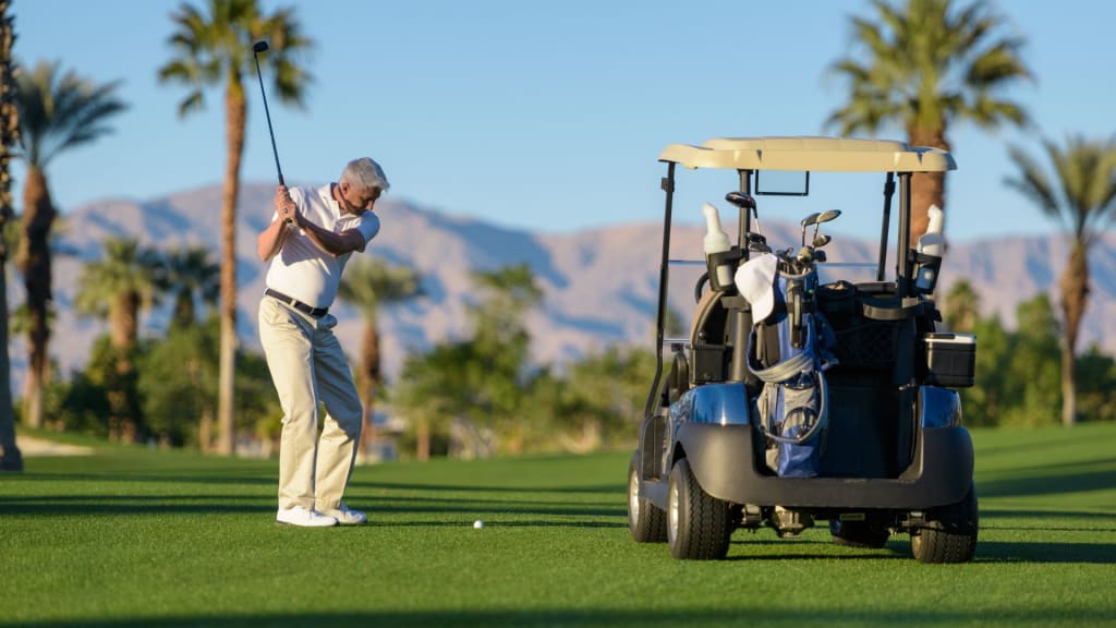 man next to a golf cart preparing to hit the ball